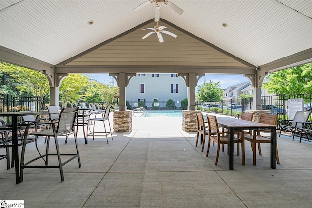 view of patio with a gazebo, fence, a community pool, a ceiling fan, and outdoor dining space