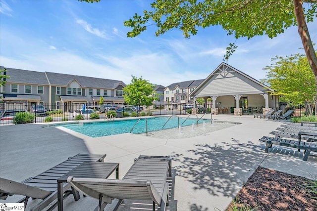 community pool with fence, a patio area, and a residential view