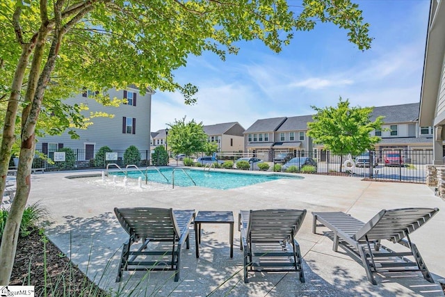 community pool with fence, a residential view, and a patio