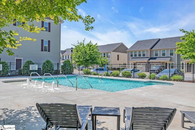 community pool featuring fence, a residential view, and a patio
