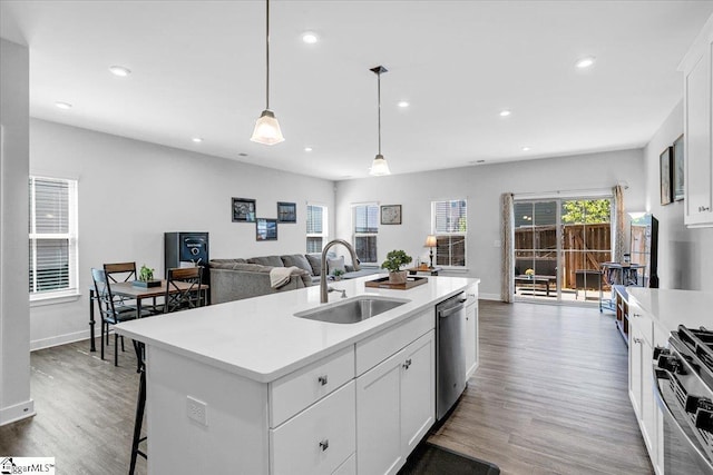 kitchen with a sink, recessed lighting, wood finished floors, light countertops, and appliances with stainless steel finishes