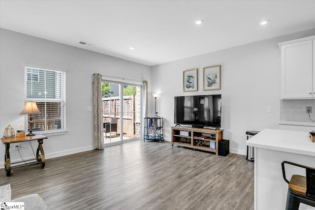 living room with recessed lighting, visible vents, light wood finished floors, and baseboards