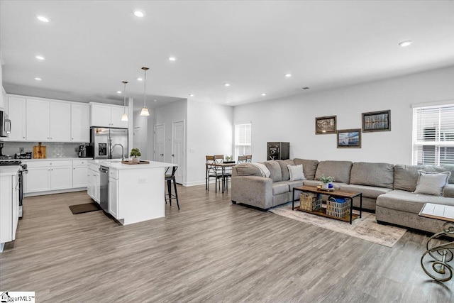 living area featuring baseboards, recessed lighting, and light wood-type flooring
