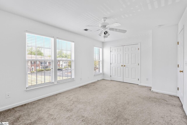 unfurnished bedroom featuring carpet floors, visible vents, a ceiling fan, and baseboards