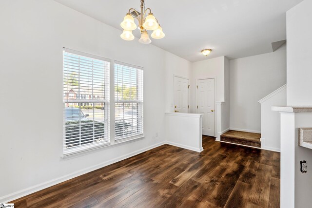 unfurnished dining area featuring a chandelier, baseboards, and dark wood-style floors