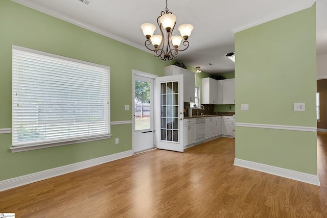 unfurnished dining area with ornamental molding, a sink, baseboards, light wood-style flooring, and a notable chandelier