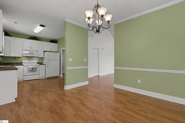 kitchen with dark countertops, a chandelier, white appliances, white cabinets, and baseboards