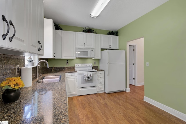 kitchen with white cabinets, white appliances, a sink, and light wood-style floors