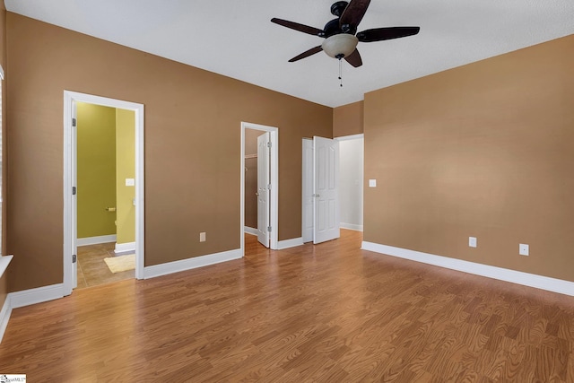 unfurnished bedroom featuring light wood-style flooring, baseboards, a spacious closet, and a closet