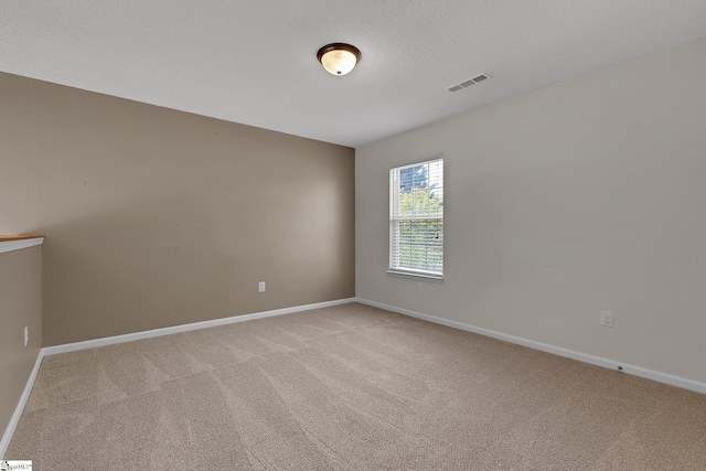 spare room with baseboards, visible vents, and light colored carpet
