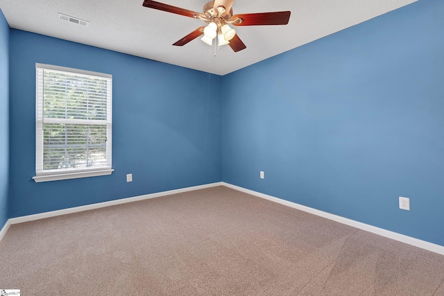 carpeted empty room with a textured ceiling, visible vents, baseboards, and ceiling fan