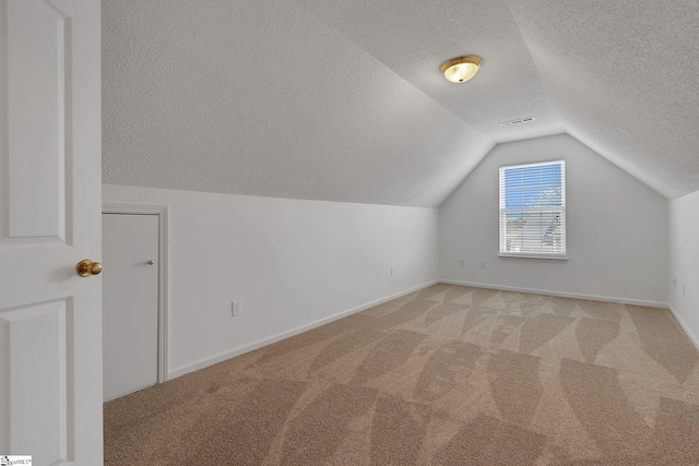 bonus room with lofted ceiling, a textured ceiling, baseboards, and light carpet