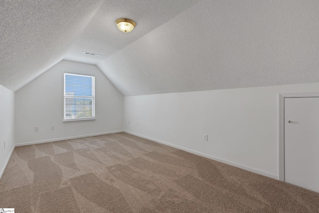 bonus room featuring vaulted ceiling, visible vents, light carpet, baseboards, and a textured ceiling