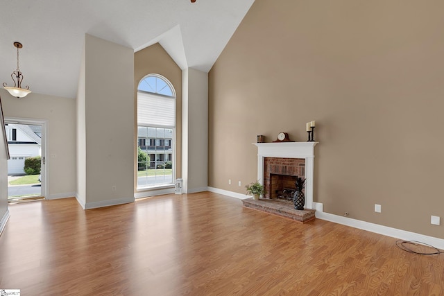 unfurnished living room with a fireplace, light wood-style floors, plenty of natural light, and high vaulted ceiling