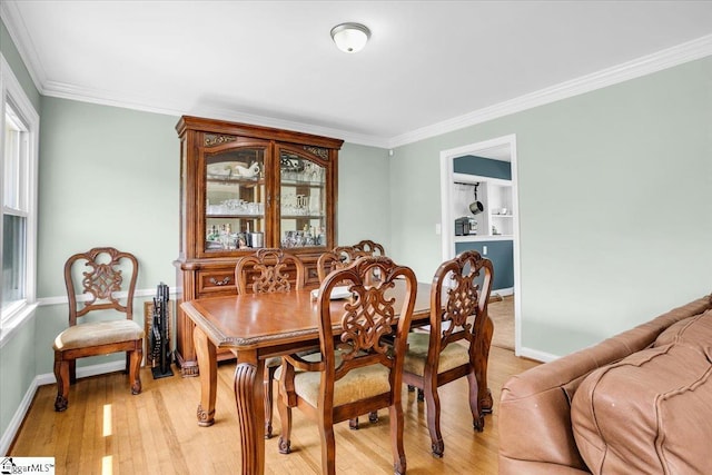 dining room with light wood-style floors, a wealth of natural light, baseboards, and ornamental molding