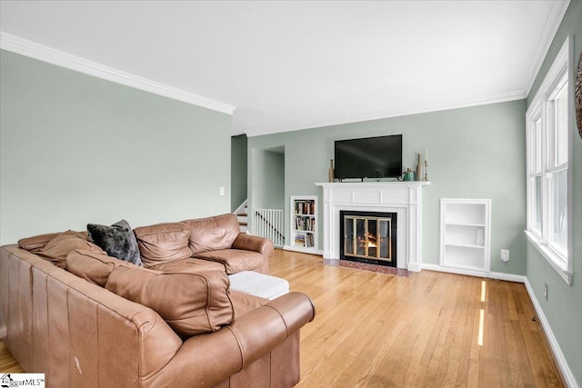 living room with a fireplace with flush hearth, light wood-style floors, stairway, and crown molding