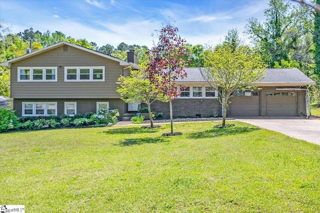 tri-level home with driveway, a chimney, brick siding, an attached garage, and a front yard