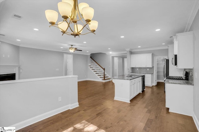 kitchen featuring ceiling fan with notable chandelier, open floor plan, visible vents, and ornamental molding