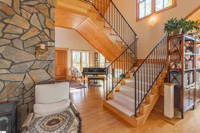 stairway featuring a wealth of natural light, wood finished floors, and a high ceiling