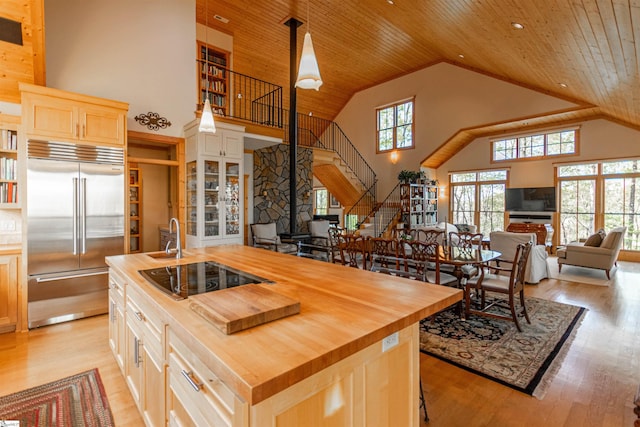 kitchen with butcher block countertops, black electric stovetop, and built in fridge