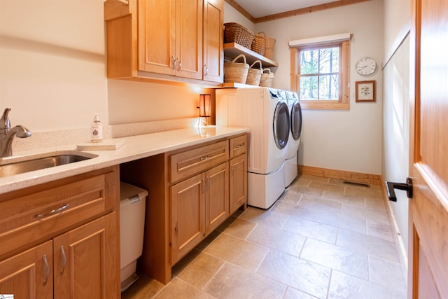 clothes washing area featuring washing machine and clothes dryer, a sink, cabinet space, baseboards, and visible vents