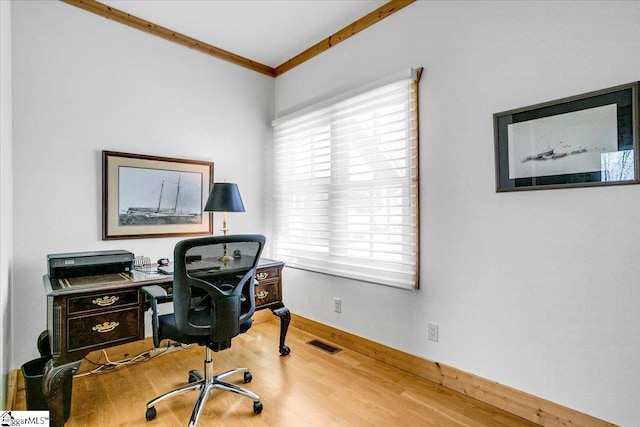 office area with crown molding, wood finished floors, visible vents, and a healthy amount of sunlight