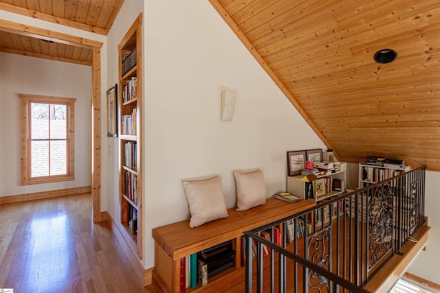 hallway with lofted ceiling, wood finished floors, an upstairs landing, baseboards, and wood ceiling