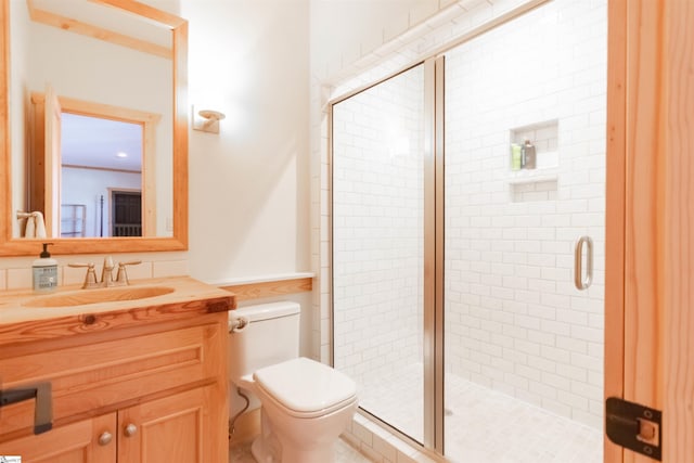 full bathroom featuring a stall shower, vanity, and toilet