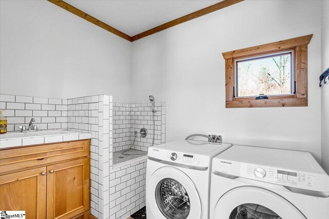 washroom with separate washer and dryer, a sink, ornamental molding, and cabinet space