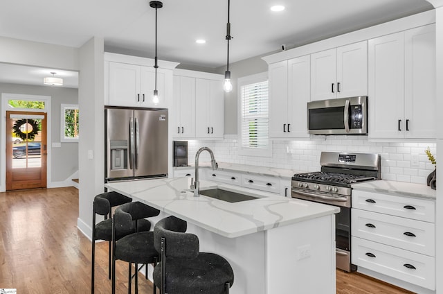 509 Dunbar St, Greenville, SC 29601 - kitchen with stainless steel appliances, backsplash, a sink, light wood-style floors, and a center island with sink