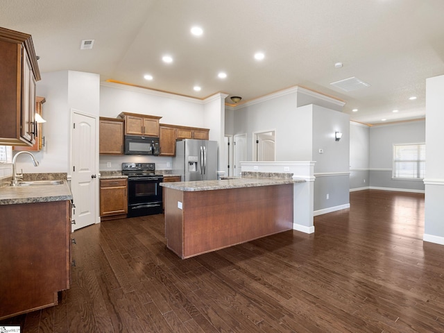 kitchen featuring crown molding, a center island, a sink, and black appliances