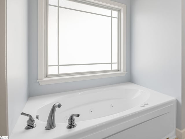 bathroom featuring plenty of natural light and a tub with jets