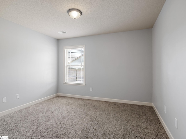 carpeted spare room with visible vents, baseboards, and a textured ceiling