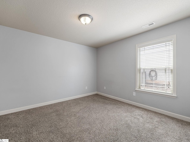 empty room with carpet, visible vents, and baseboards