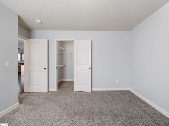 unfurnished bedroom featuring a spacious closet, baseboards, carpet, and a closet