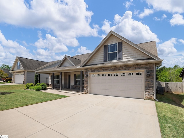 craftsman inspired home with a front lawn, driveway, stone siding, covered porch, and fence