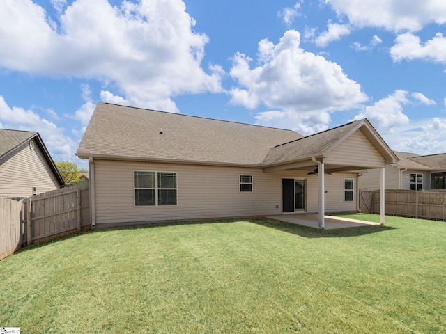 rear view of house with a ceiling fan, a shingled roof, a fenced backyard, a yard, and a patio area