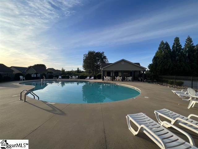 community pool with a patio area and fence