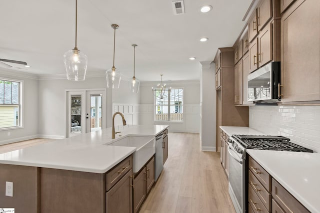 kitchen with visible vents, ornamental molding, a sink, light wood-style flooring, and appliances with stainless steel finishes