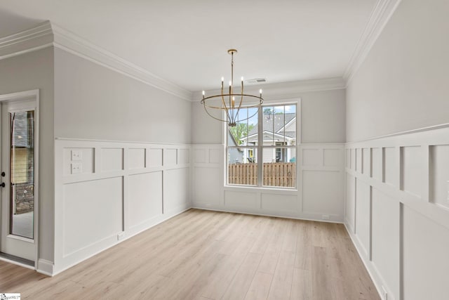 unfurnished dining area featuring a decorative wall, crown molding, a chandelier, and light wood-type flooring