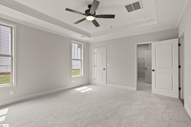 unfurnished bedroom featuring a tray ceiling, carpet, baseboards, ornamental molding, and visible vents