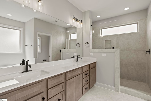 bathroom featuring tile patterned flooring, double vanity, a sink, and a walk in shower