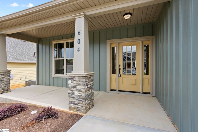 property entrance with board and batten siding, a porch, and central air condition unit