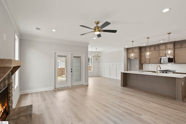 unfurnished living room with recessed lighting, ornamental molding, a lit fireplace, and ceiling fan with notable chandelier