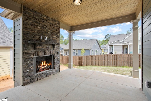 view of patio with fence, an outdoor stone fireplace, and a residential view