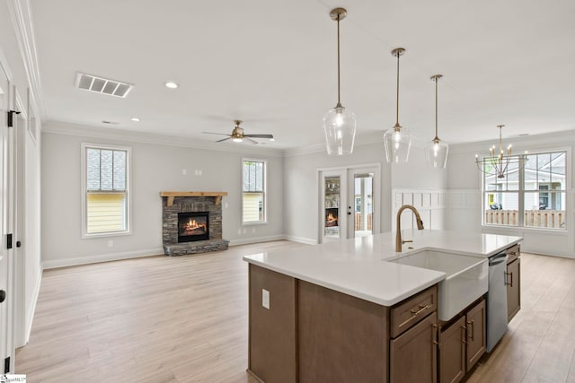 kitchen with a sink, visible vents, ceiling fan with notable chandelier, dishwasher, and a stone fireplace