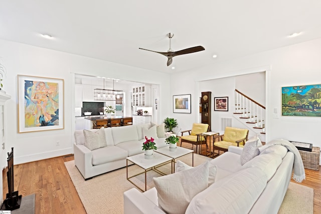 living room featuring ceiling fan, stairs, light wood finished floors, and recessed lighting