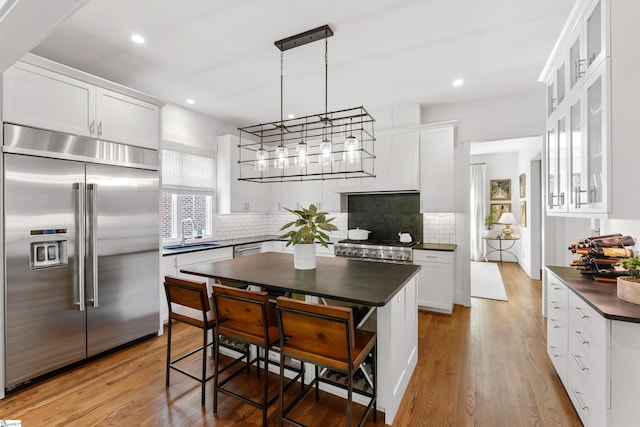 kitchen featuring dark countertops, a sink, decorative backsplash, appliances with stainless steel finishes, and recessed lighting