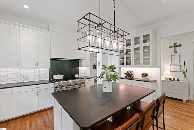 kitchen featuring white cabinets, dark countertops, decorative backsplash, and double oven range