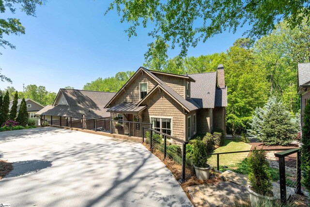 view of front of property with fence, a shingled roof, a chimney, and concrete driveway